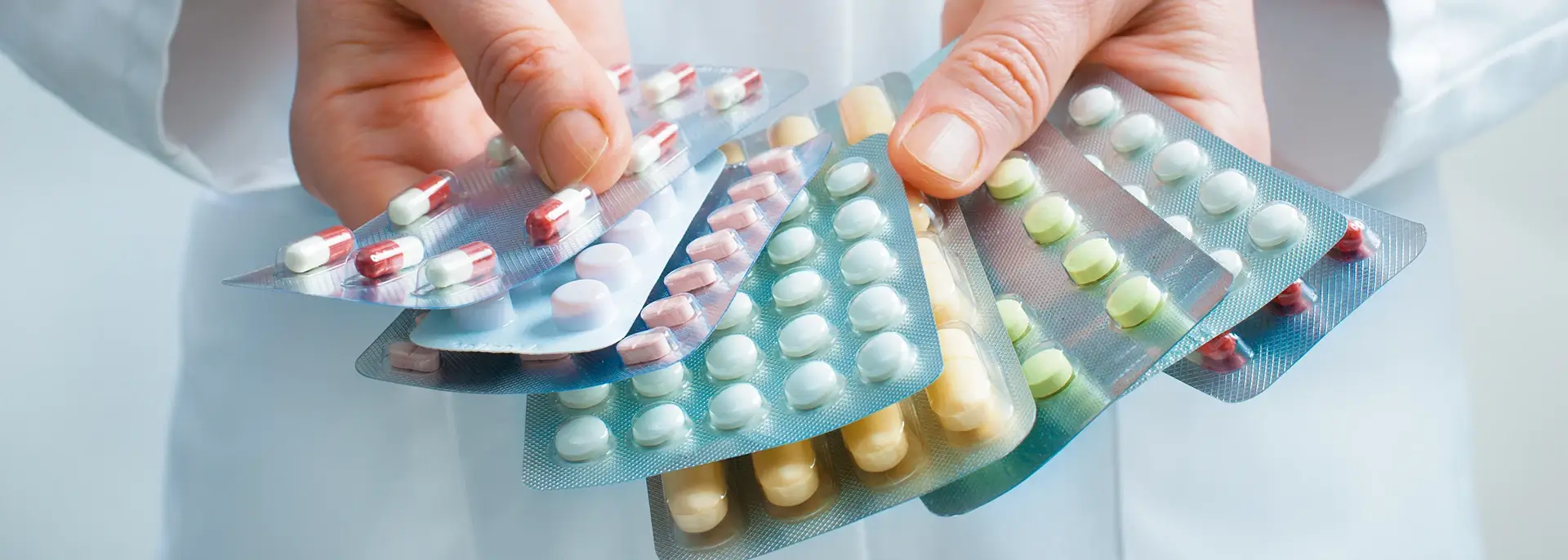 Doctor holding out several packs of a variety of pills