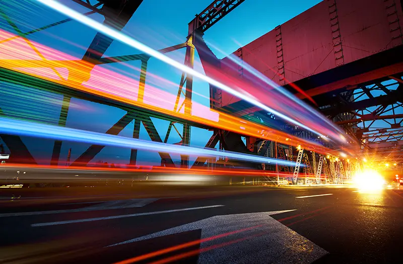 Car lights streaking by on a bridge