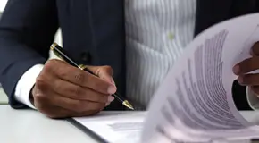 Guy in suit signing legal documents with pen and paper