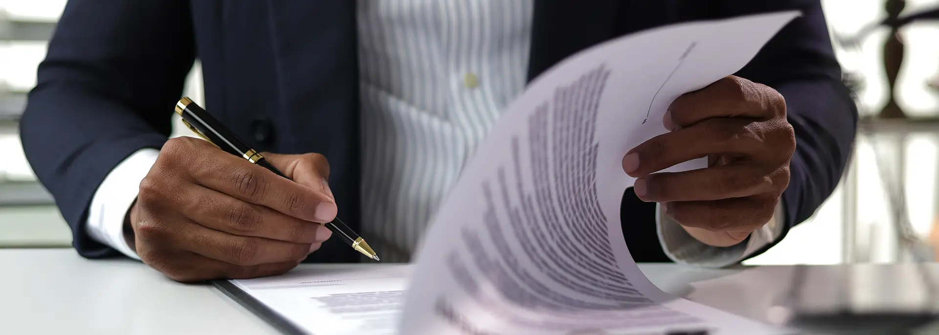 Guy in suit signing legal documents with pen and paper