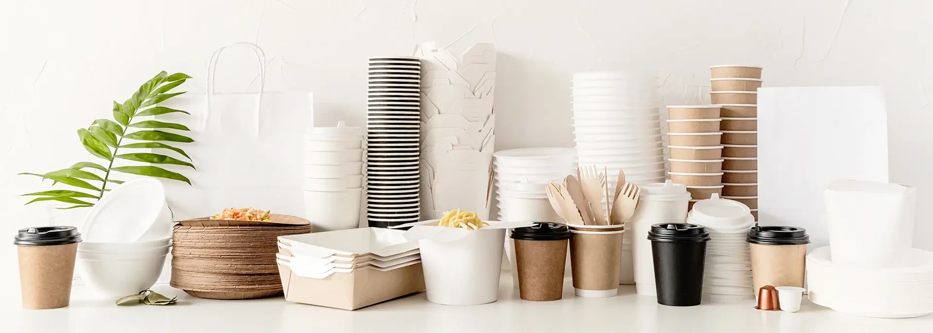 Assortment of stacked disposable coffee cups, coffee lids, oyster pails, and utensils