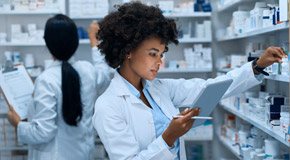 Two pharmacists back to back checking medications on shelves