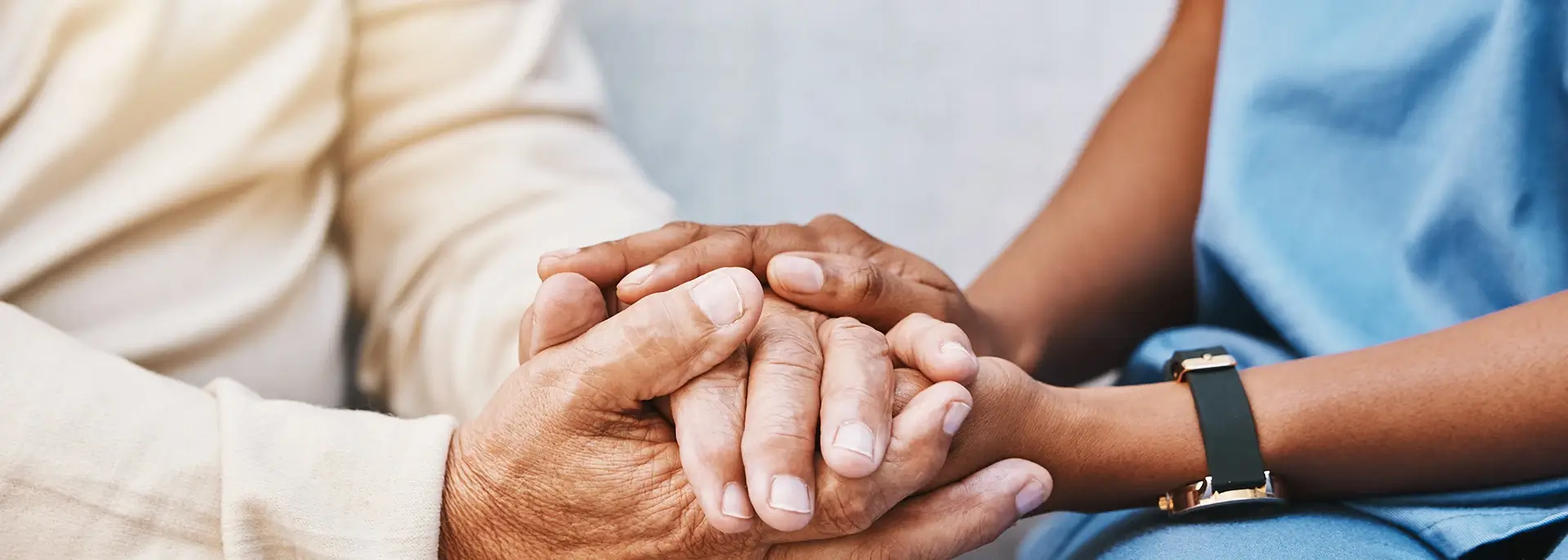 Close-up of elderly person and medical worker holding hands