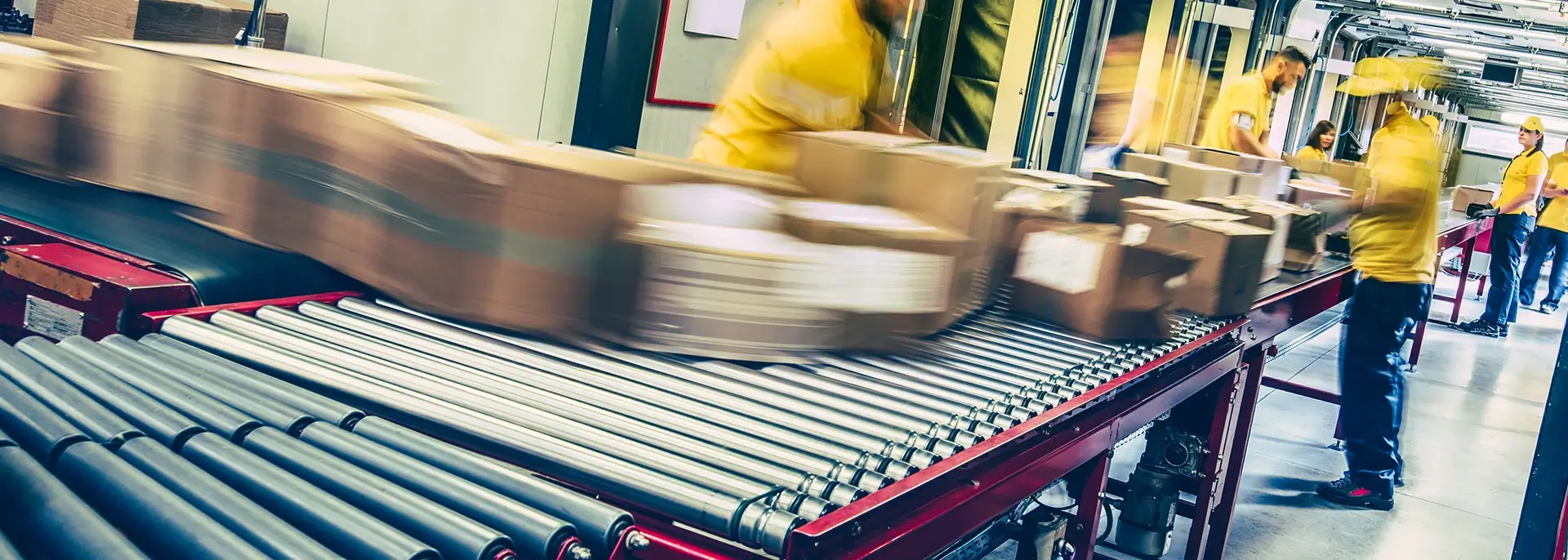 Workers in yellow rolling packages down a conveyor belt